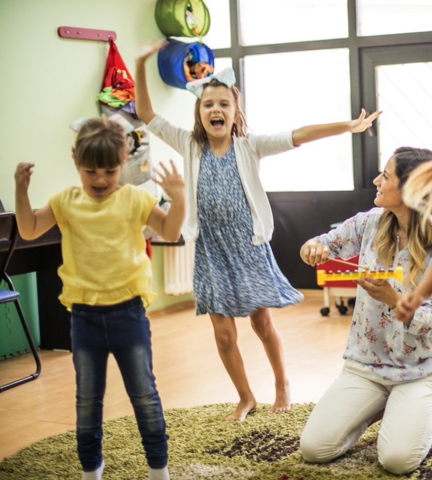 Children dancing beside their music teacher